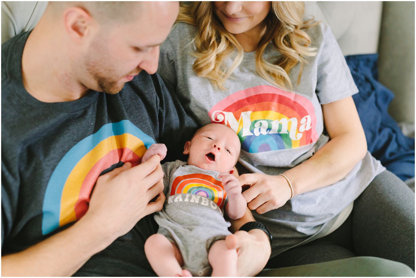 parents snuggling newborn wearing rainbow shirts