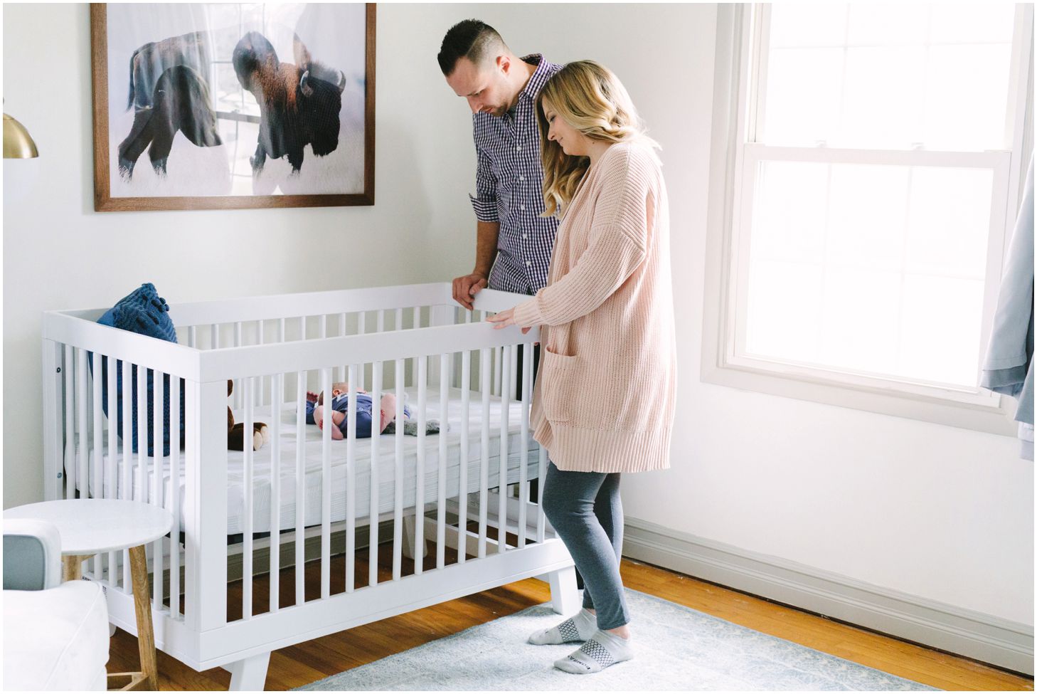 parents looking into crib at newborn, modern nursery