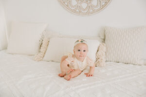 six month old baby girl on white bed, sitter session