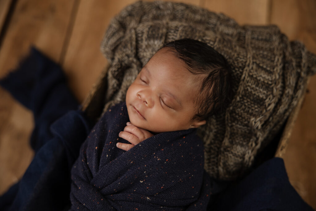 sleeping newborn wrapped in navy blankets