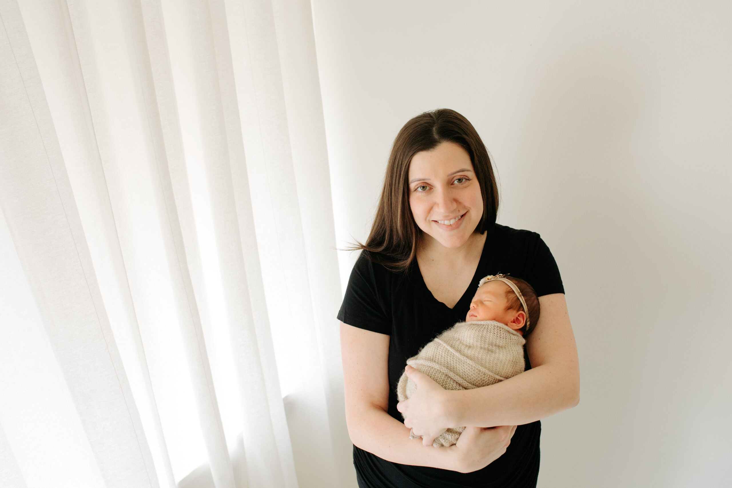 New mom in black for a studio family session with their newborn girl, captured by Kelly Adrienne Photography