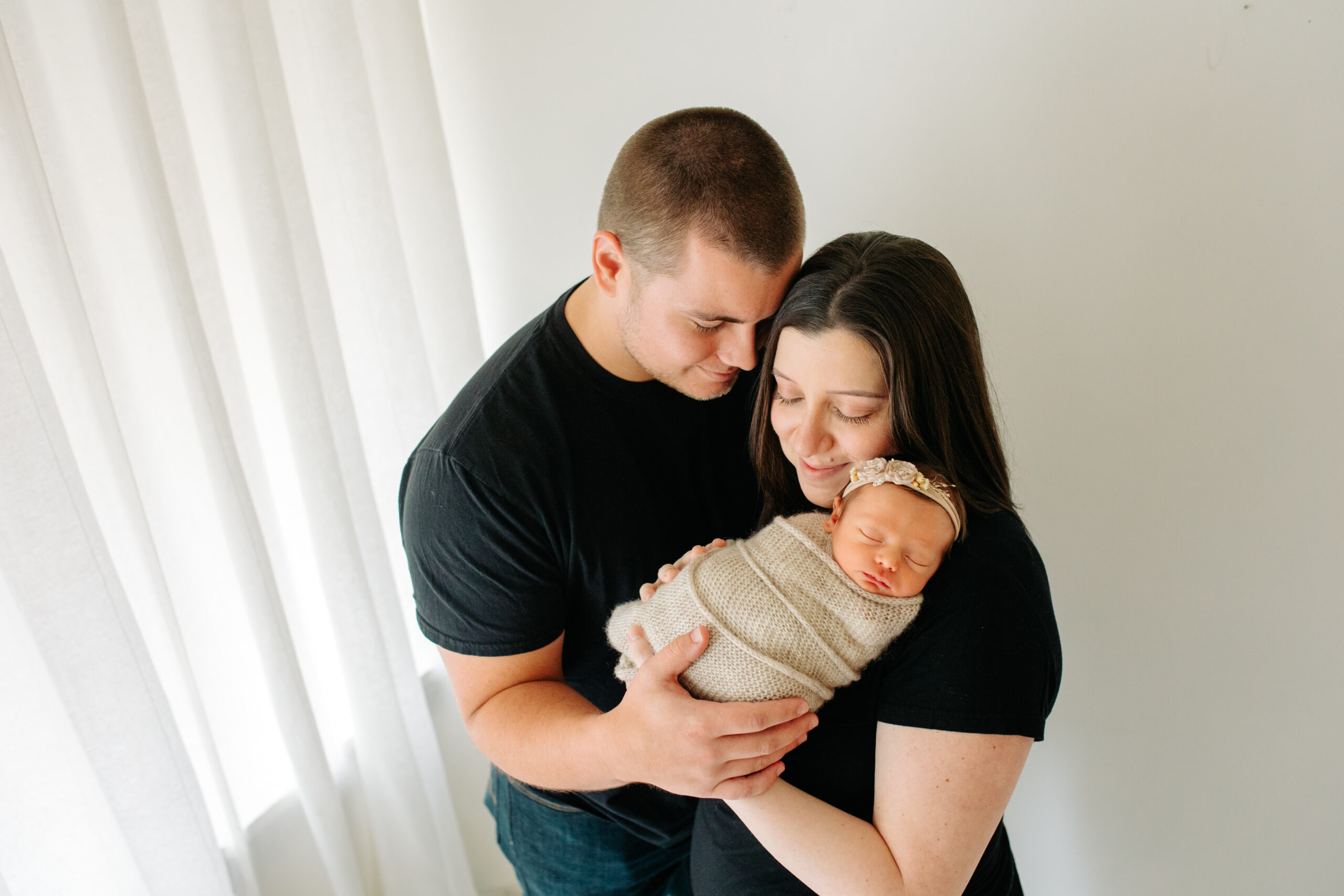 New parents in black for a studio family session with their newborn girl, captured by Kelly Adrienne Photography