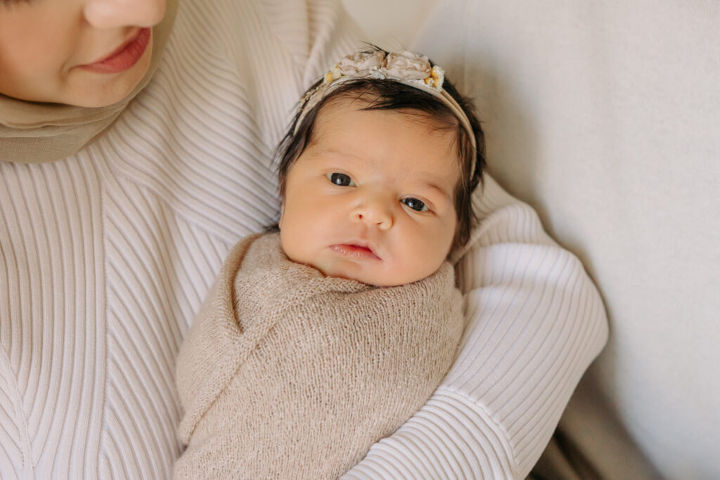 Wide-eyed newborn girl in neutrals at Kelly Adrienne Photography studio