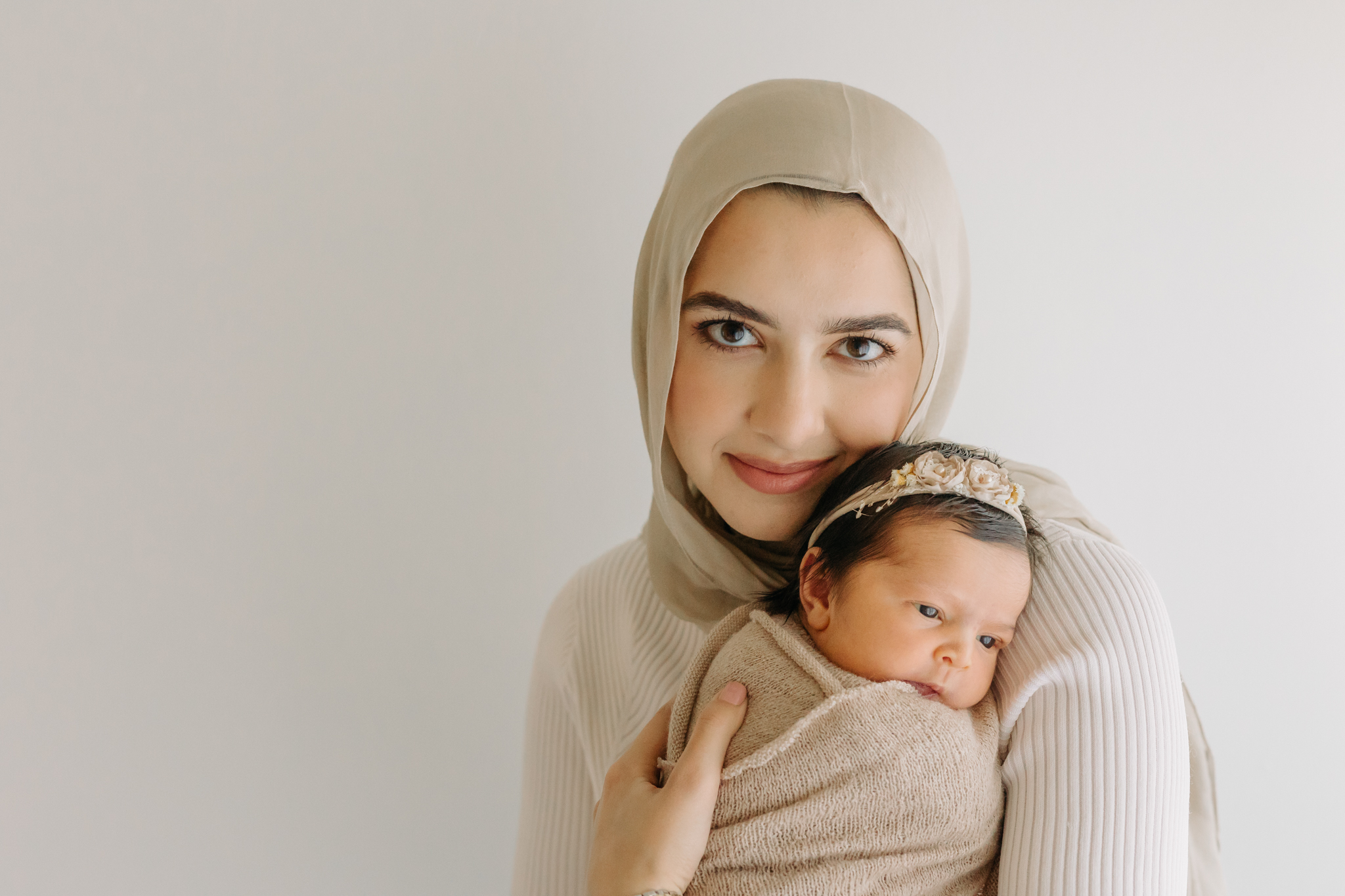 Beautiful new mom in hijab snuggling her dark-haired baby girl captured by Kelly Adrienne Photography