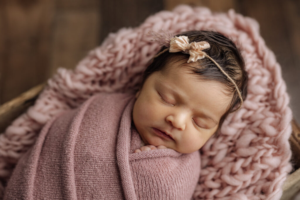 Sleeping dark haired newborn girl in dusty pink at Kelly Adrienne Photography studio