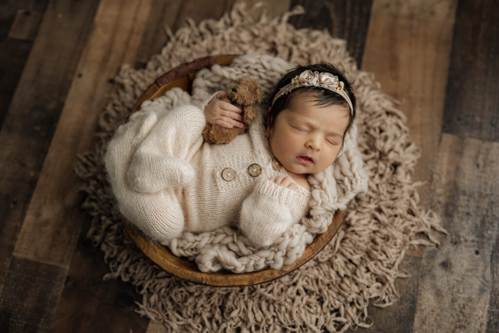 Sleeping dark haired newborn girl in neutral bowl setup at Kelly Adrienne Photography studio