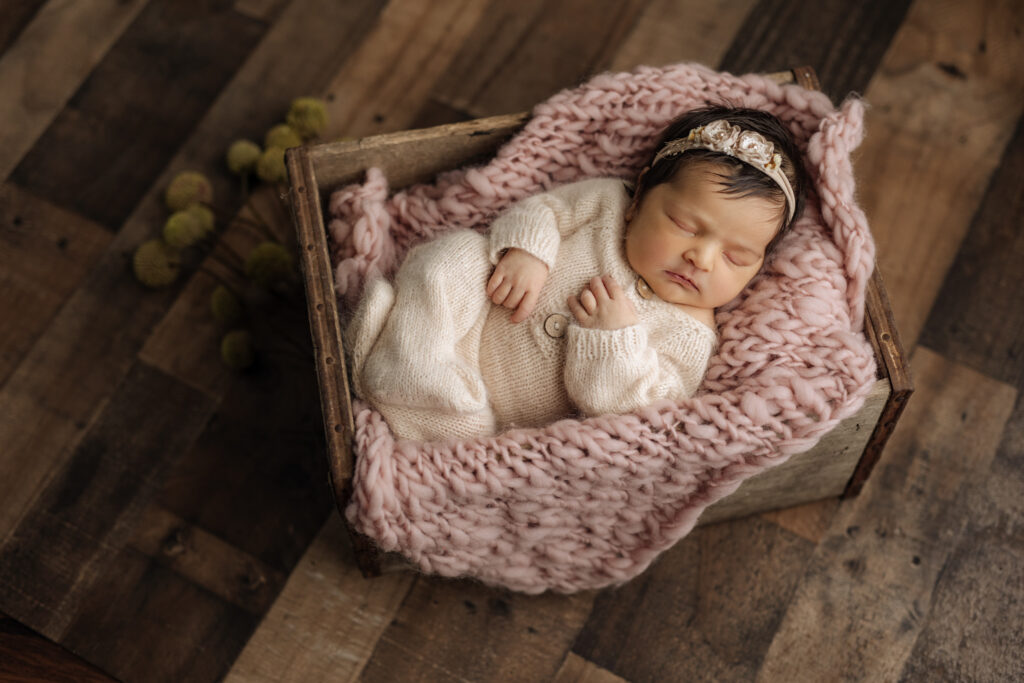 Sleeping dark haired newborn girl in neutral bowl setup at Kelly Adrienne Photography studio