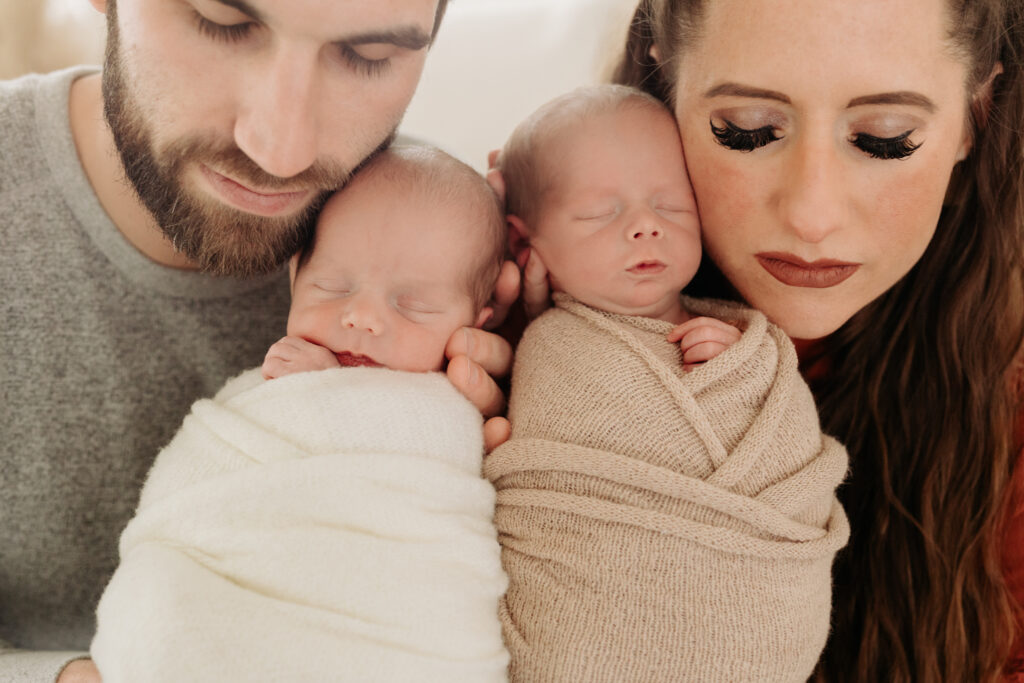 intimate twin newborn family session detail with mom and dad snuggling together