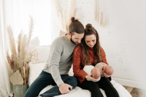 twin newborn boho family session on white bed with grasses
