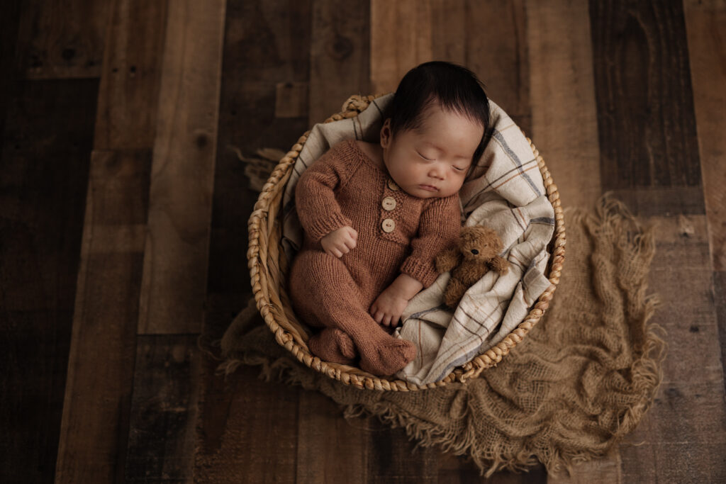 baby boy newborn session with pajamas sleeping in a basket