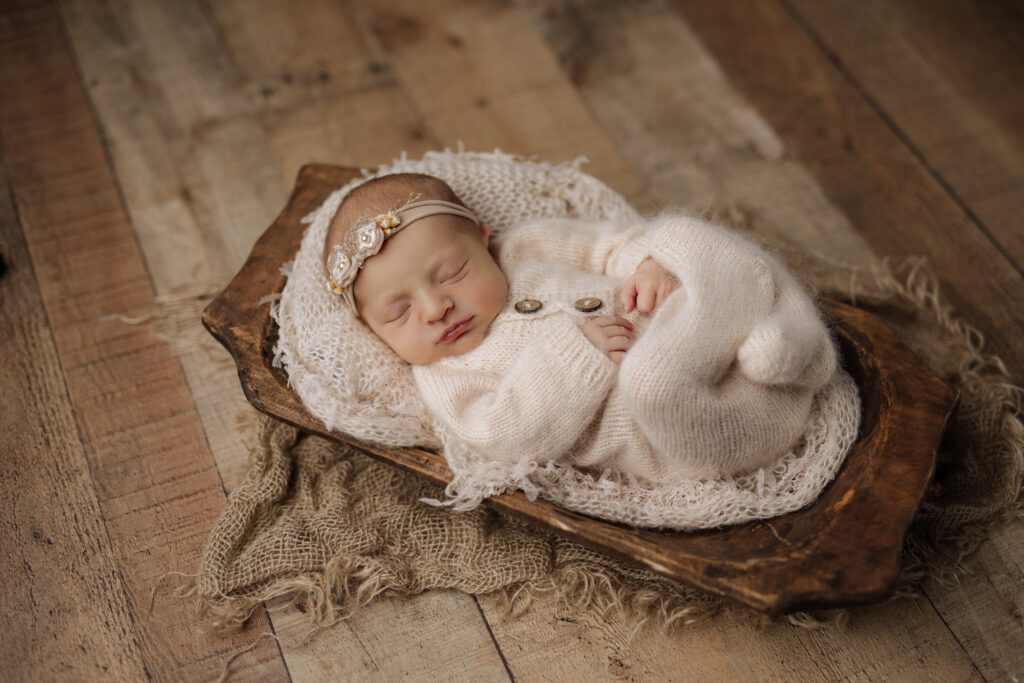 Natural newborn setup with baby in cream pajamas