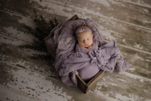 sleeping newborn baby wrapped in shades of purple