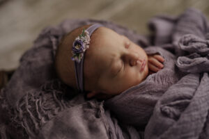 sleeping newborn baby wrapped in shades of purple