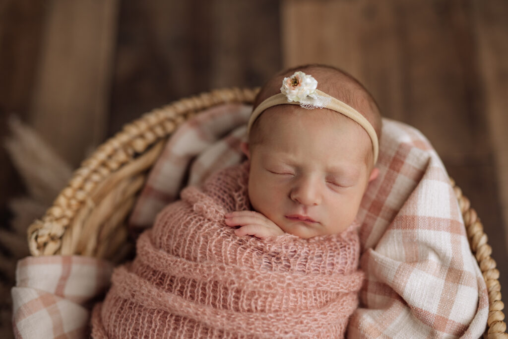 sleeping newborn baby wrapped in a pink blanket with a headband