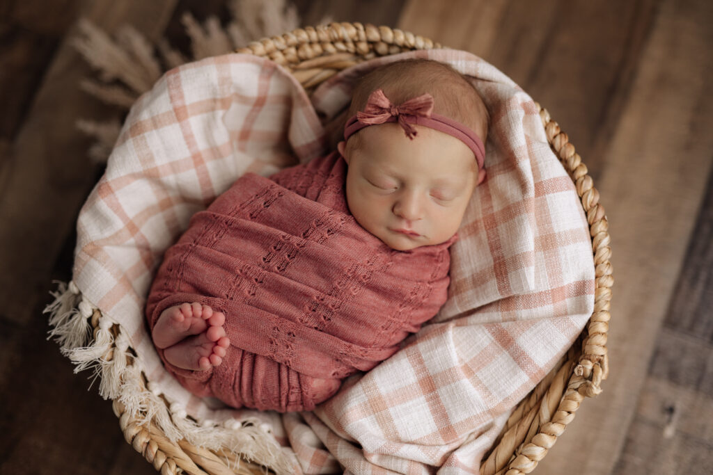 baby with toes sticking out swaddled in a mauve antique blanket