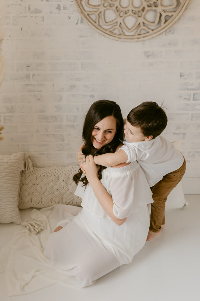 Indoor maternity session, white studio, mother and son hugging