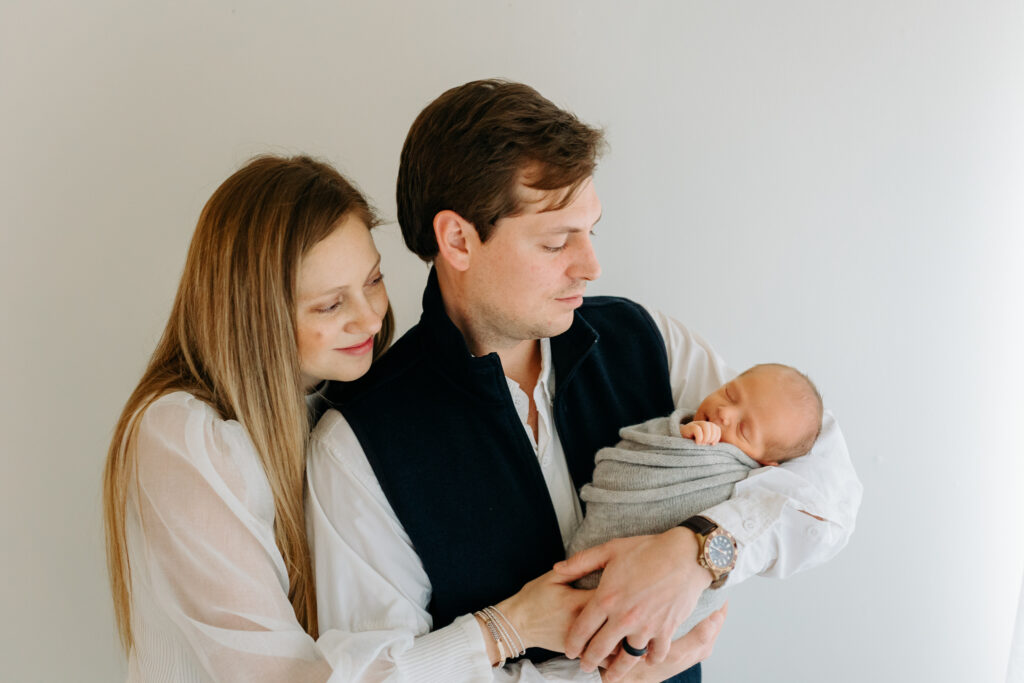 parents snuggling their newborn at his baby photos | Kelly Adrienne Photography