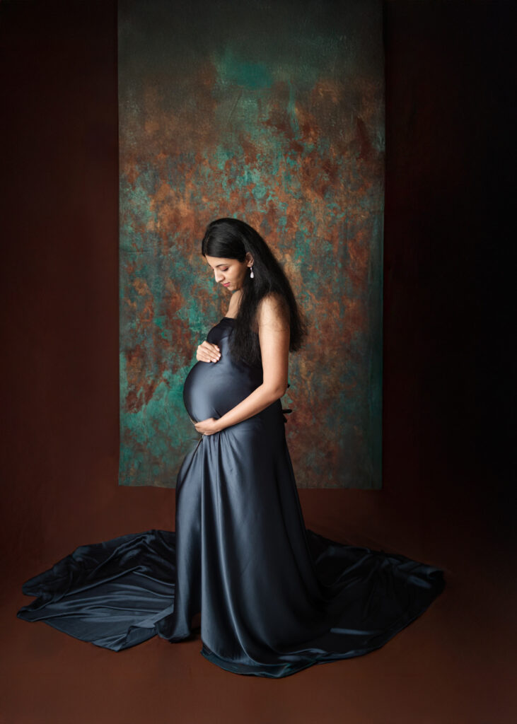 blue silk maternity dress on brown and blue backdrop