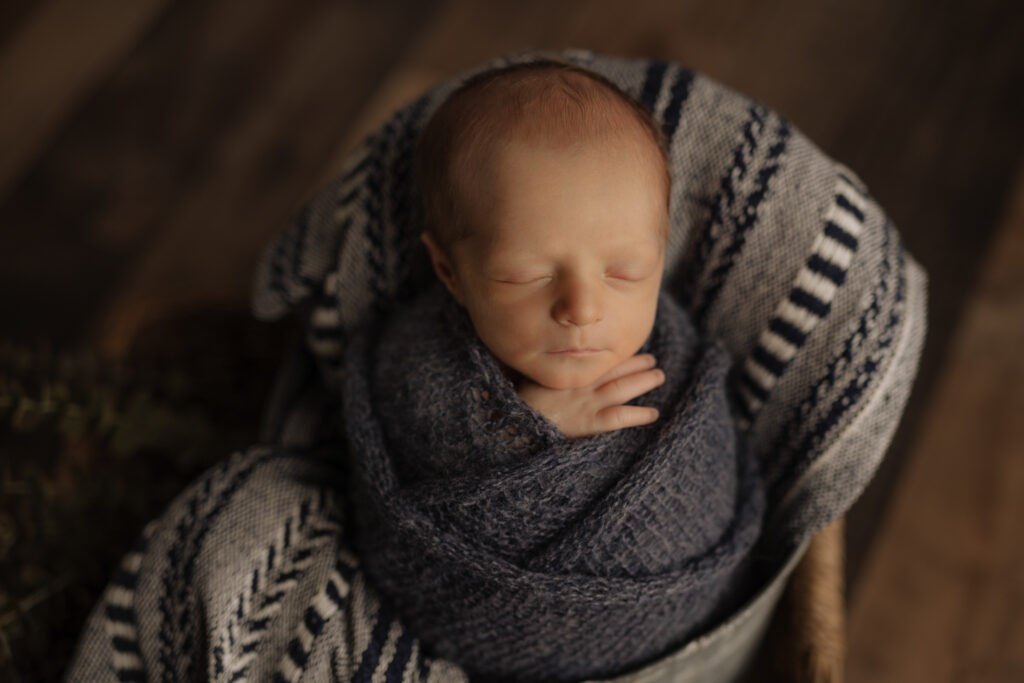newborn wrapped in blue in basket at Kelly Adrienne Photography studio