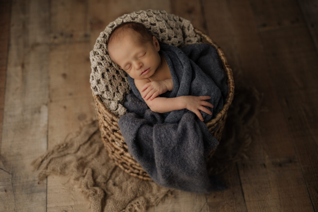 newborn wrapped in blue in basket prop at Kelly Adrienne Photography studio