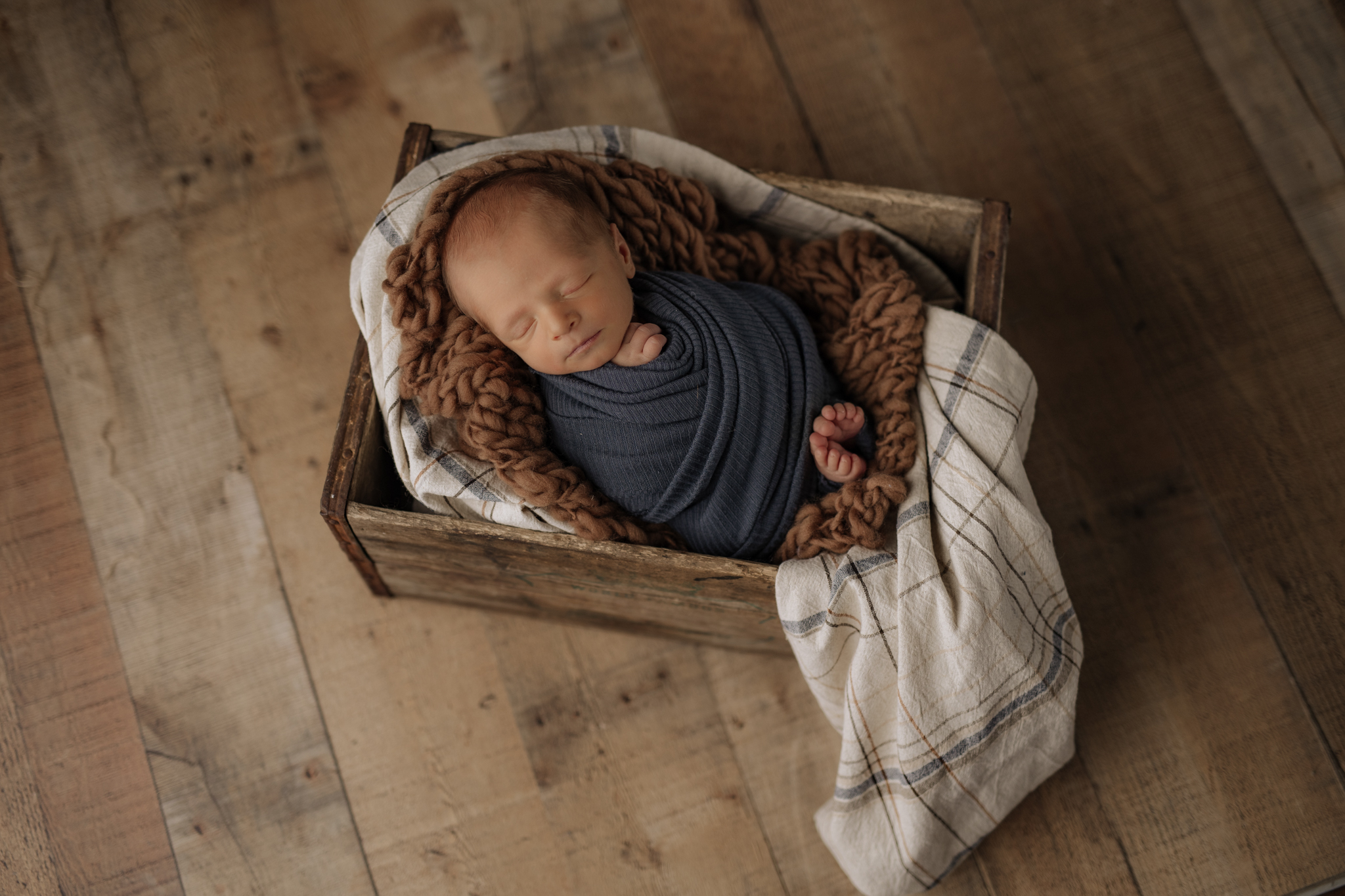 newborn wrapped in blue in wood crate prop at Kelly Adrienne Photography studio
