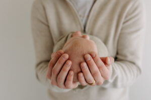 dad holds his newborn baby against a white background