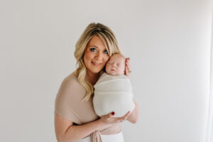 mom snuggles with her newborn baby against a white background