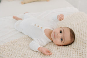 3-month old boy lying on bed in all white studio