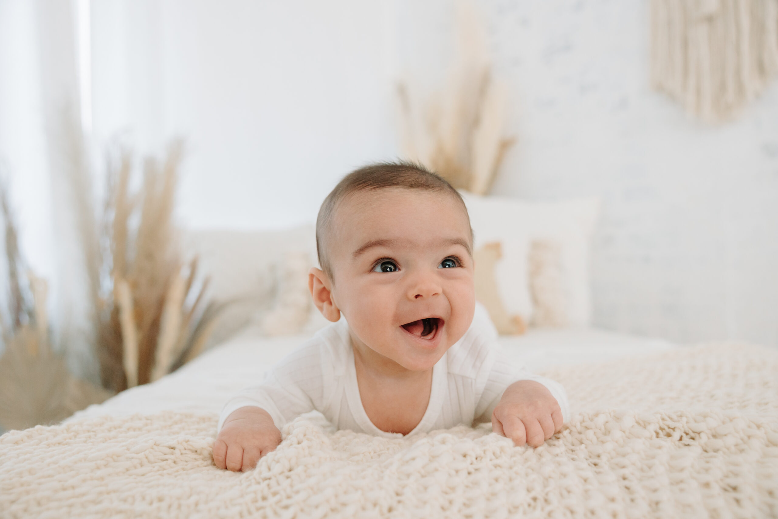 smiling 3-month old baby boy on white bed