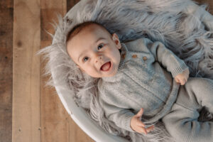 3 month old baby laughing in a white bowl with gray fur