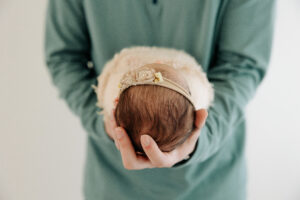 detail photo of newborn's hair and headband while dad holds her