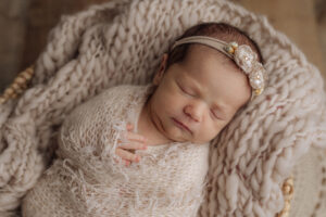 sweet baby girl swaddled in a cream wrap with matching headband