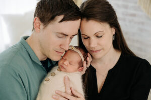 mom and dad snuggle together with their newborn baby girl, detail