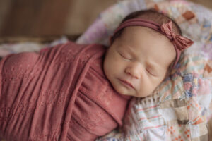 sweet sleeping newborn swaddled in pink with a matching headband