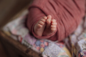 detail of newborn baby toes with an antique quilt and pink wrap