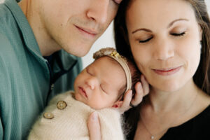 mom and dad snuggle together with their newborn baby girl, detail