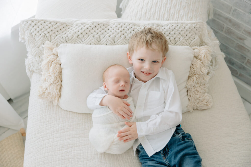 Newborn session with toddler | toddler boy holds his newborn baby brother in a boho studio | Kelly Adrienne Photography