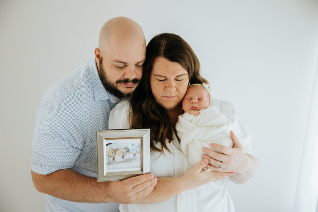 Parents holding a memorial photo and their newborn girl at Wexford photography studio