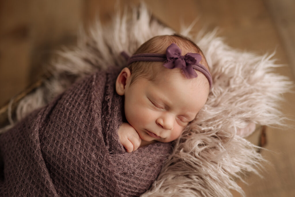 Newborn girl photoshoot with purple wrap and headband at Kelly Adrienne Photography