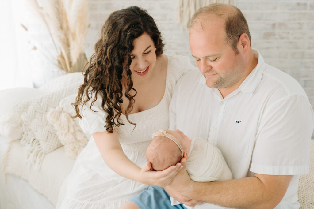 mom and dad holding newborn daughter at photo studio in Pittsburgh