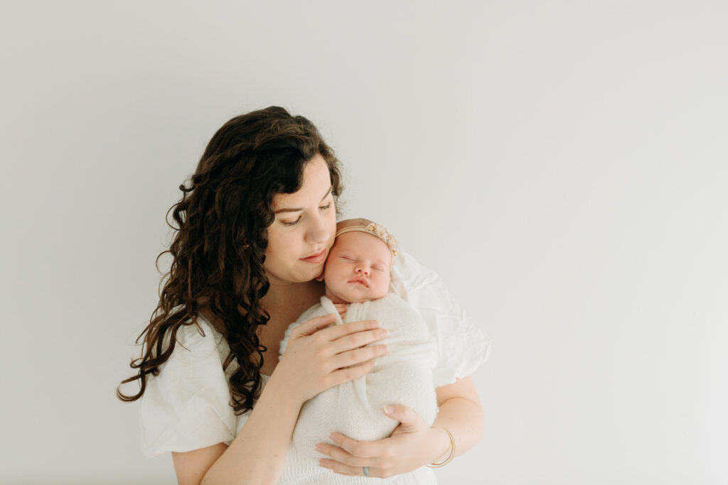 mom holding newborn daughter at photo studio in Pittsburgh