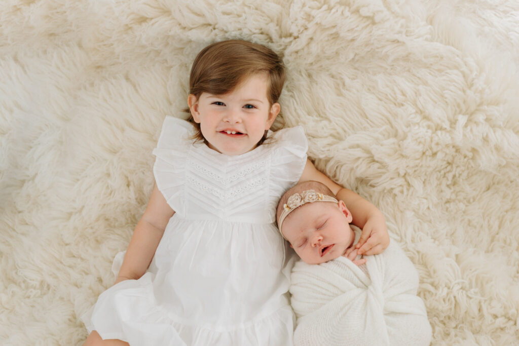 Toddler girl holding newborn sister at photo session in Pittsburgh