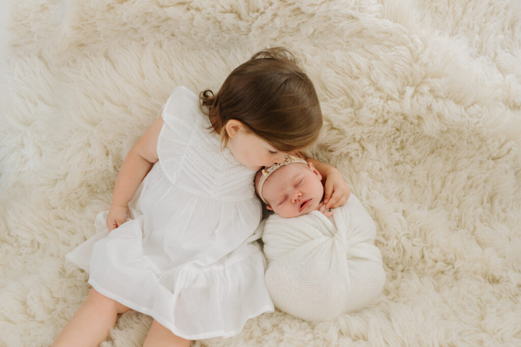 Toddler girl holding newborn sister at photo session in Pittsburgh