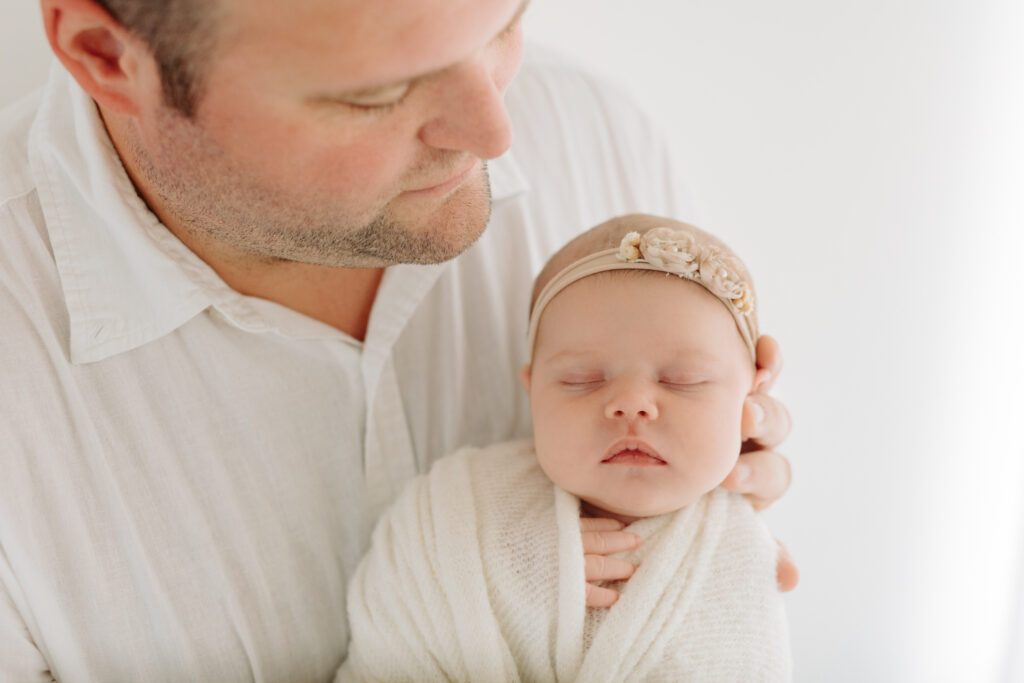 close-up of dad holding newborn daughter at photo studio in Pittsburgh