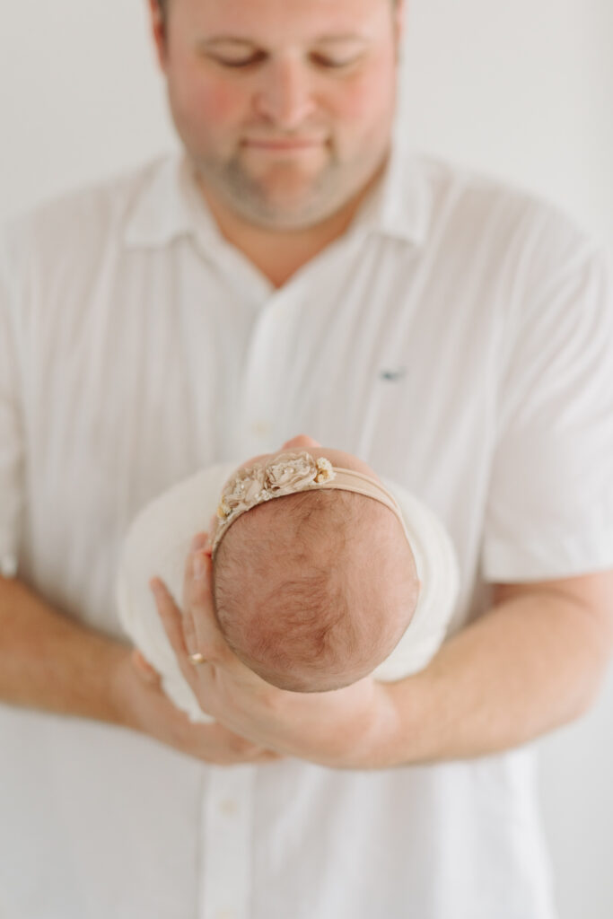 close-up of dad holding newborn daughter at photo studio in Pittsburgh