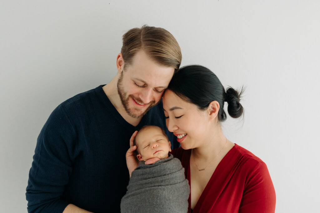 mom, dad, and newborn baby pose for photographers