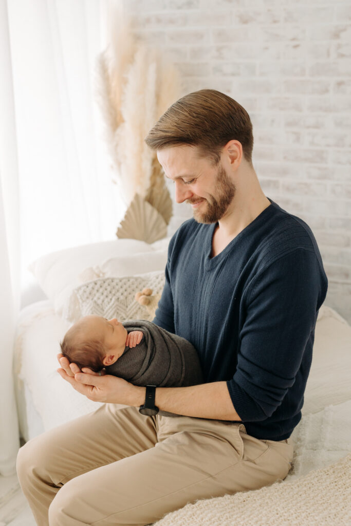 dad holding baby boy at newborn photography studio