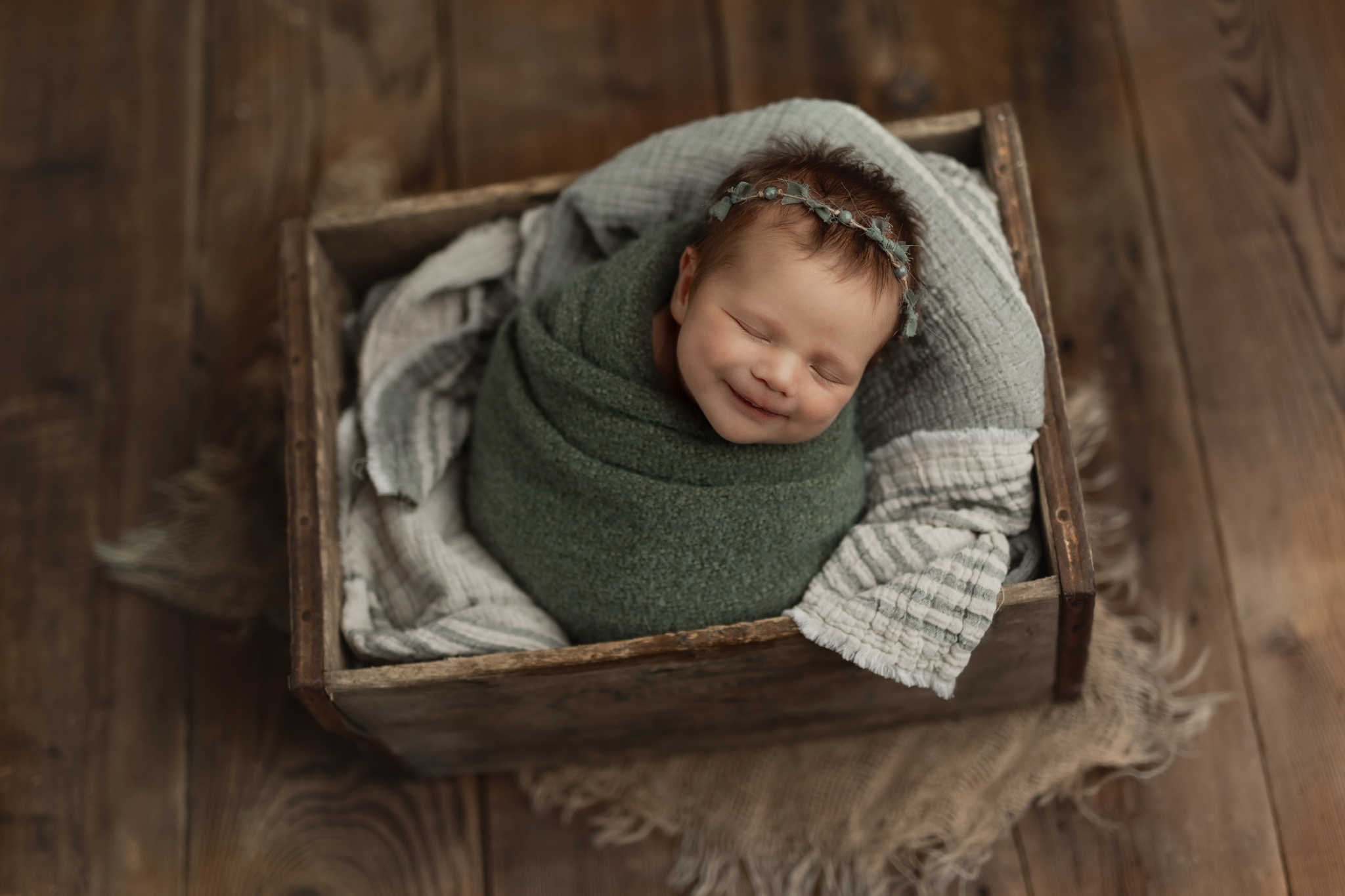 Baby girl in green smiling at her newborn photography shoot in Pittsburgh 