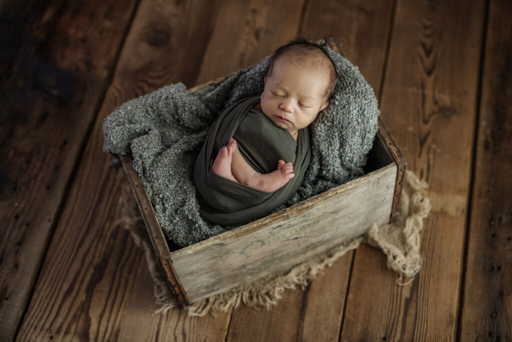 Little boy in green egg wrap at newborn photo shoot in Pittsburgh