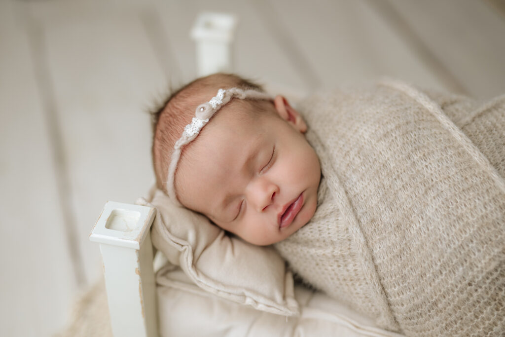 baby wrapped in tan on bed, newborn photography